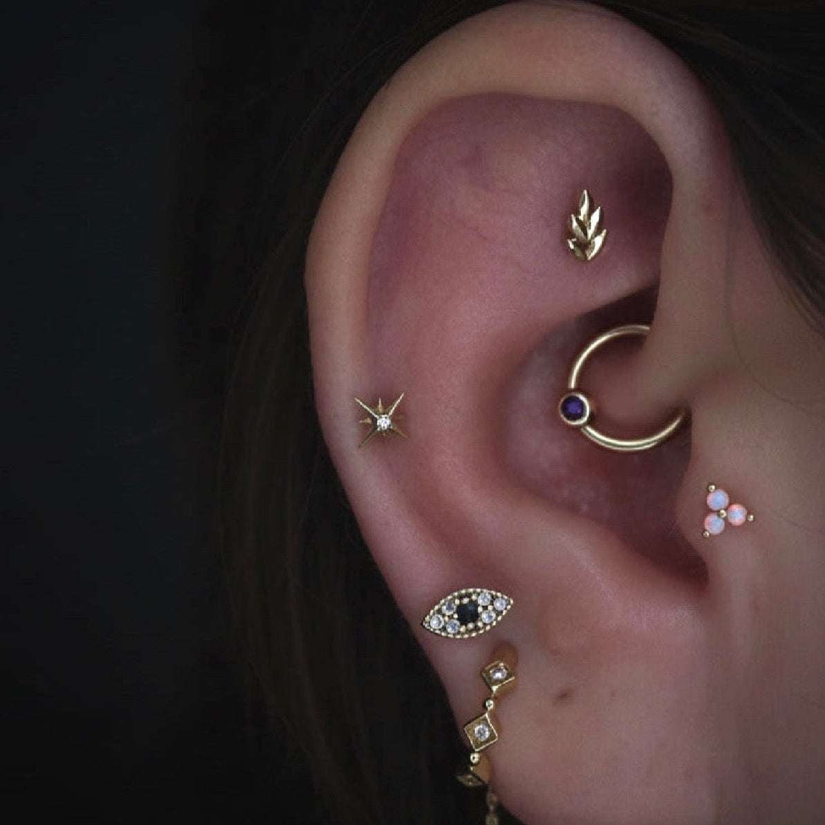 Curated ear styled with solid 14k gold star earrings layered with complementary cartilage jewellery.