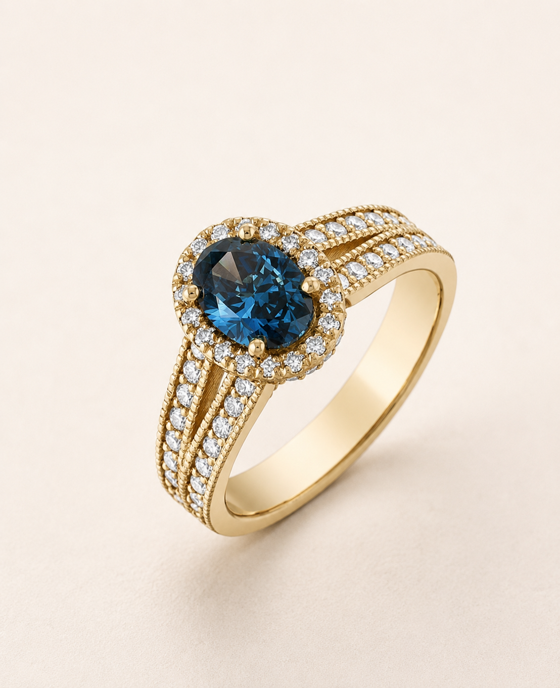 BVLA bespoke yellow gold engagement ring featuring an oval blue sapphire with a diamond halo and triple diamond set shoulders in a handcrafted luxury custom design.