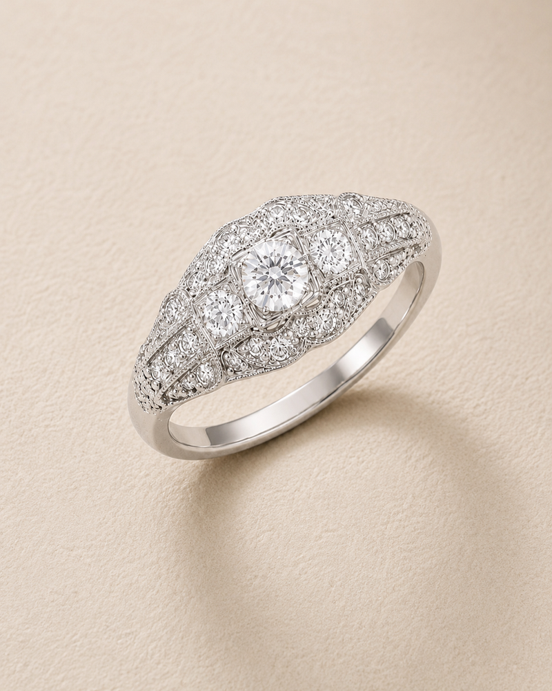 Vintage-inspired BVLA bespoke white gold engagement ring with a round brilliant diamond, intricate milgrain detailing and pavé diamond accents.