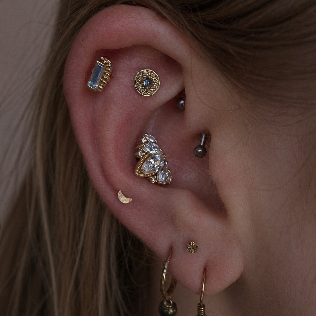 Luxury curated ear featuring the BVLA Elizabeth in the rook, BVLA Beaded Baguette Rainbow Moonstone in the helix, Junipurr Queen Naveen in the conch, and stacked gold lobe jewellery.