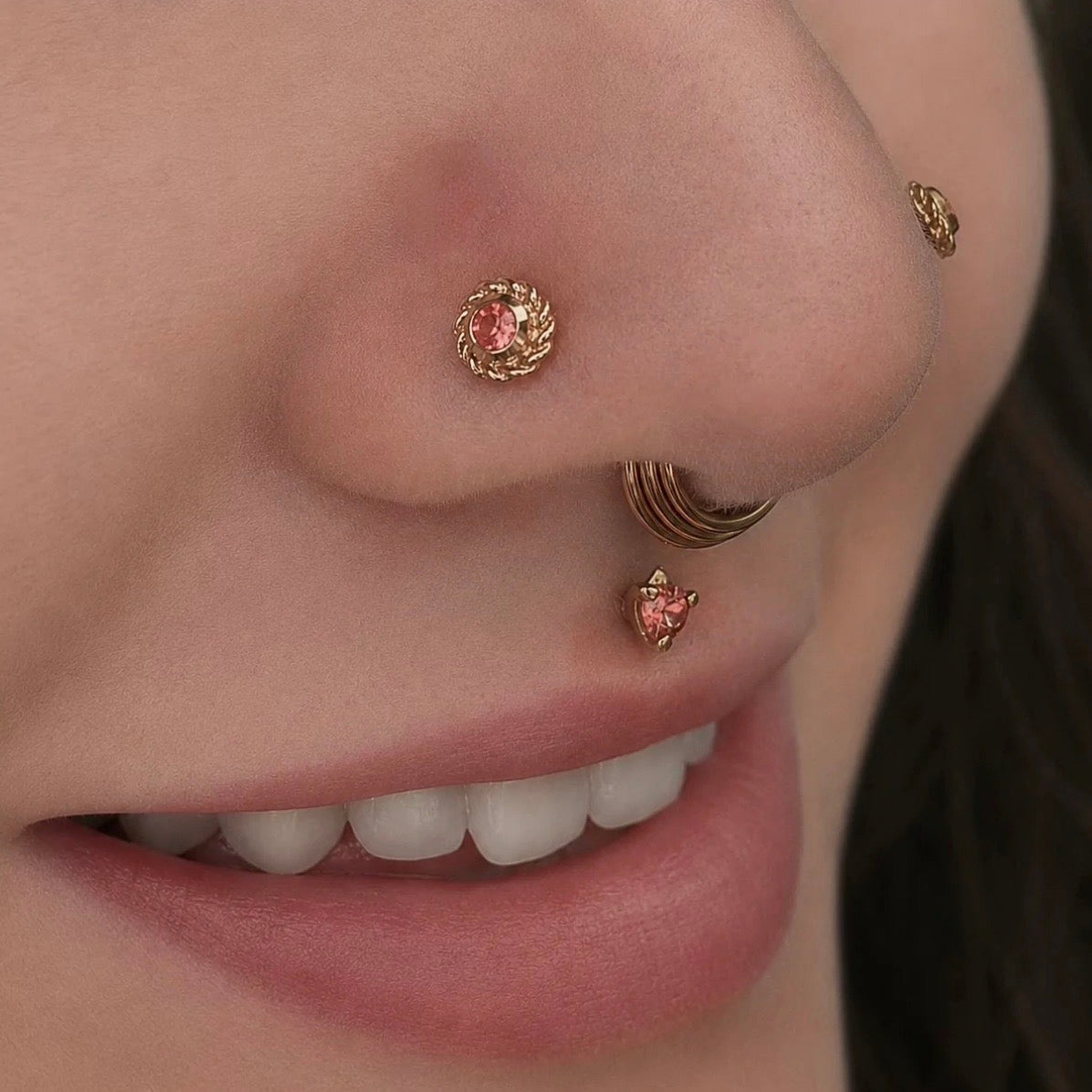 Close-up of a curated facial piercing featuring BVLA Timka ends in a philtrum piercing and double nostril piercings with solid 14k yellow gold jewellery.