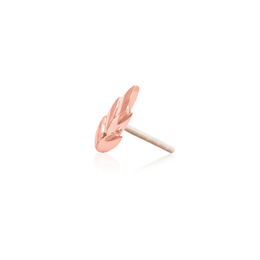 Solid rose gold leaf end positioned along a flat ear piercing for soft organic detail.