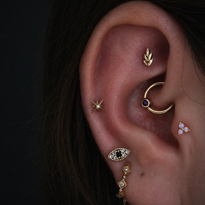 Solid gold fern leaf stud styled with complementary helix, cartilage and lobe earrings in a curated ear.