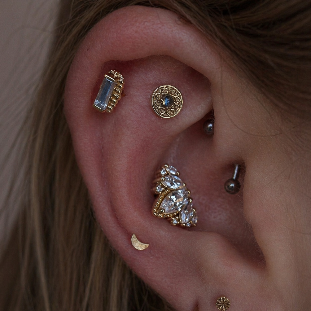 Junipurr Engraved Disk solid 14k gold star cartilage stud worn in a minimalist curated ear with complementary gold jewellery.