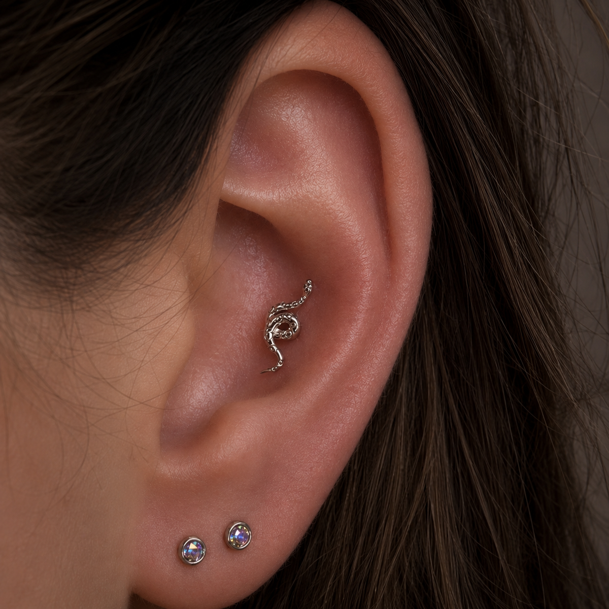 The Junipurr Textured Snake in white gold styled in the conch piercing, paired with a rook hoop and stacked lobe hoops for an elegant curated ear.
