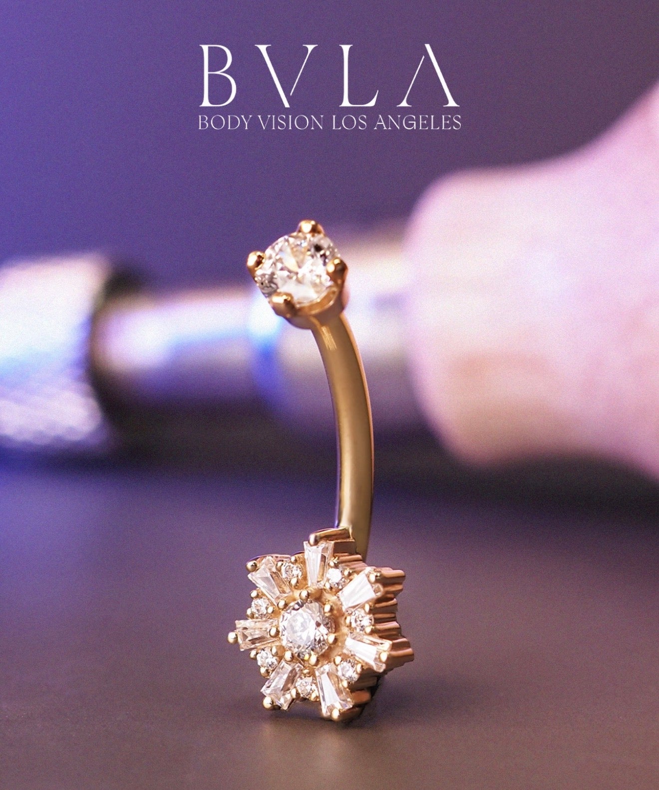 Close-up of a BVLA solid 14k gold curved navel bar featuring a floral diamond design, styled as luxury belly button piercing jewellery.