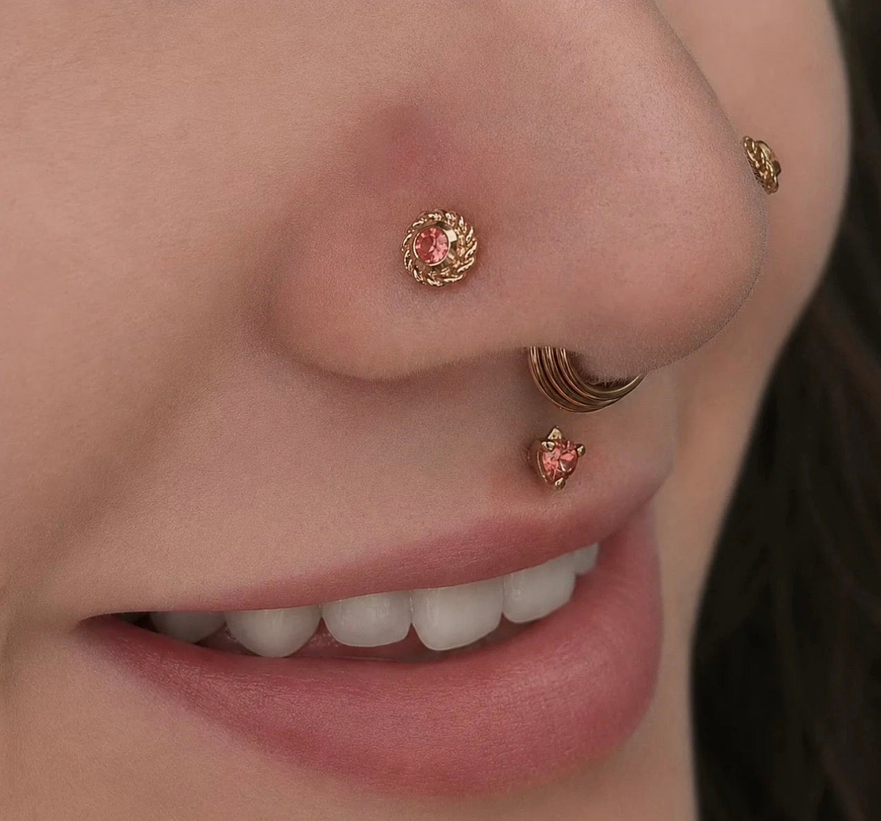 Close-up of double nostril piercings featuring the BVLA Choctaw 14k gold nose stud with a gemstone centre, paired with a Timka philtrum piercing and a gold nose ring for luxury facial jewellery styling.