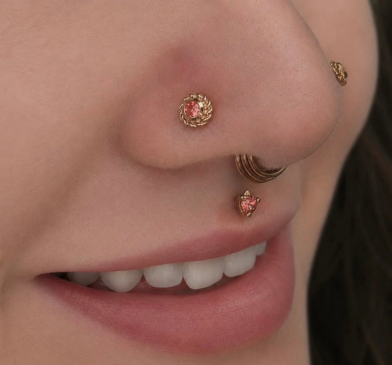 Close-up of double nostril piercings featuring the BVLA Choctaw 14k gold nose stud with a gemstone centre, paired with a Timka philtrum piercing and a gold nose ring for luxury facial jewellery styling.