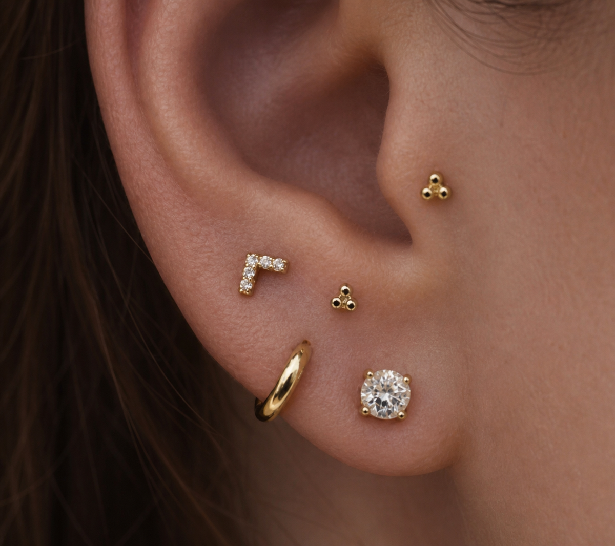 Curated lobe piercings styled with gold and diamond jewellery