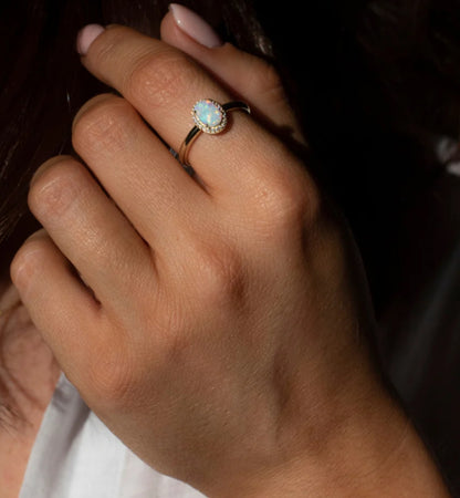 Junipurr Uzara gold ring with a 5mm × 7mm opal and cubic zirconia halo, product view.